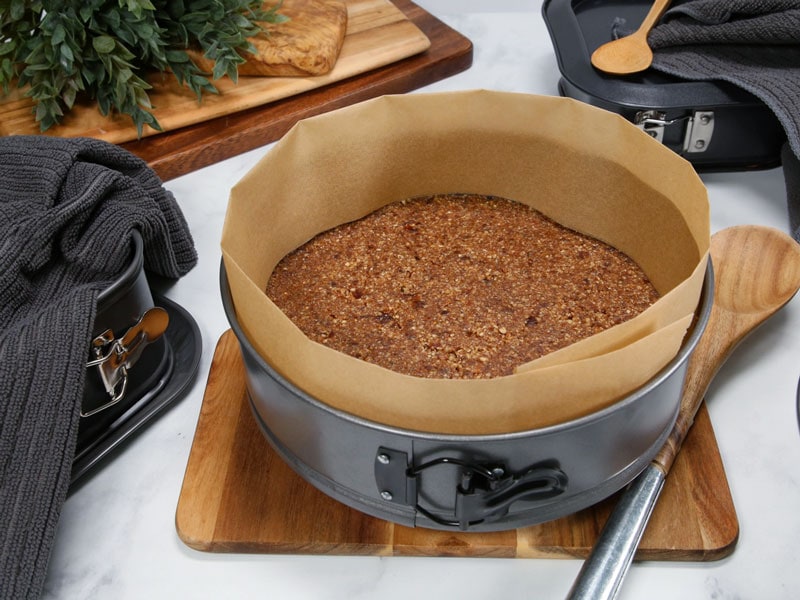A 9-inch springform pan lined with a round of parchment paper on the bottom, sitting on a kitchen counter