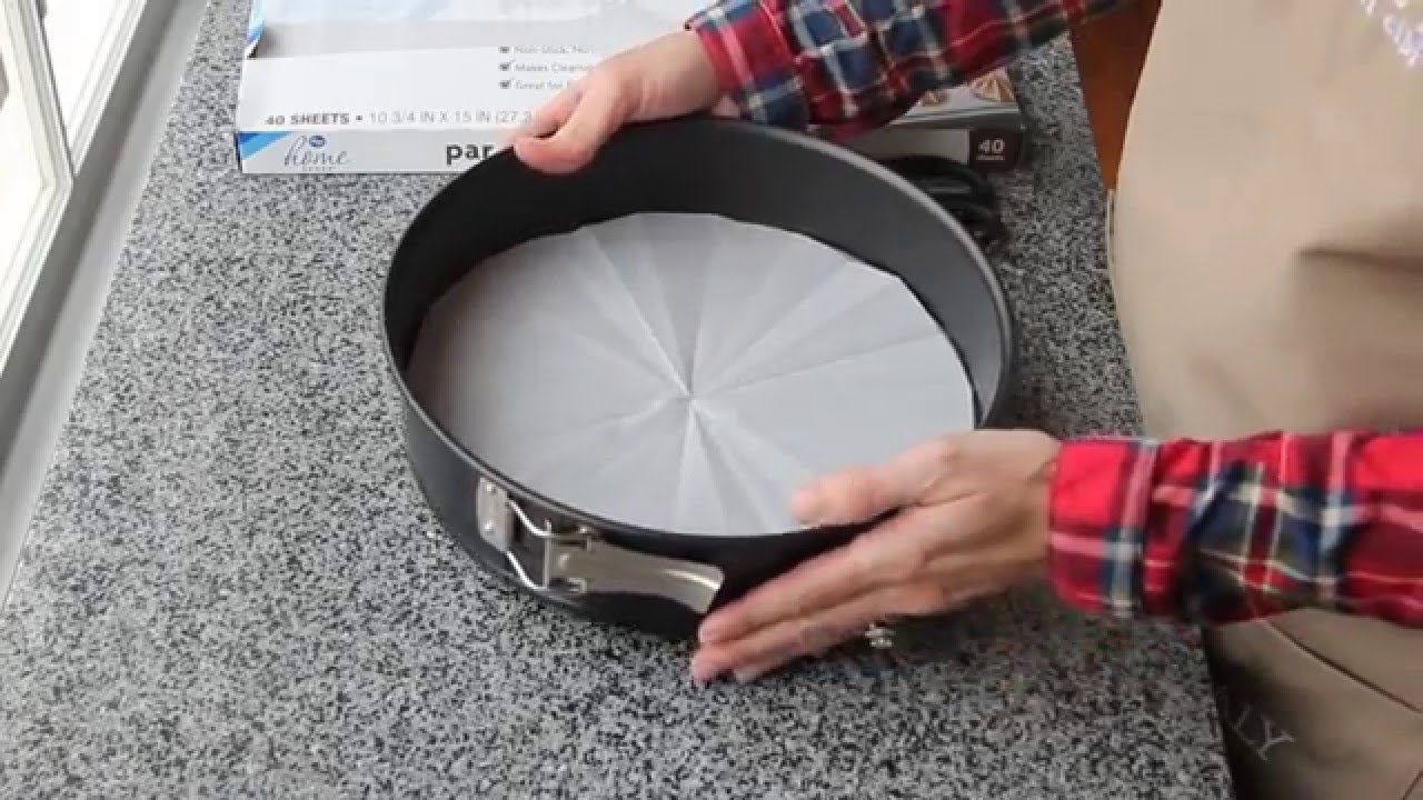 A 9-inch springform pan lined with parchment on the bottom and lightly greased, sitting on a kitchen counter