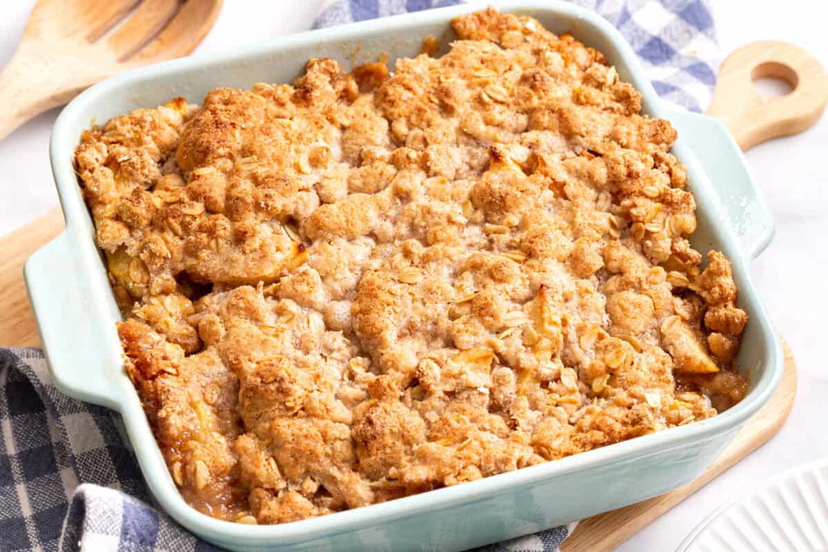 A baked apple crumble cooling in a square baking dish with a golden crisp topping