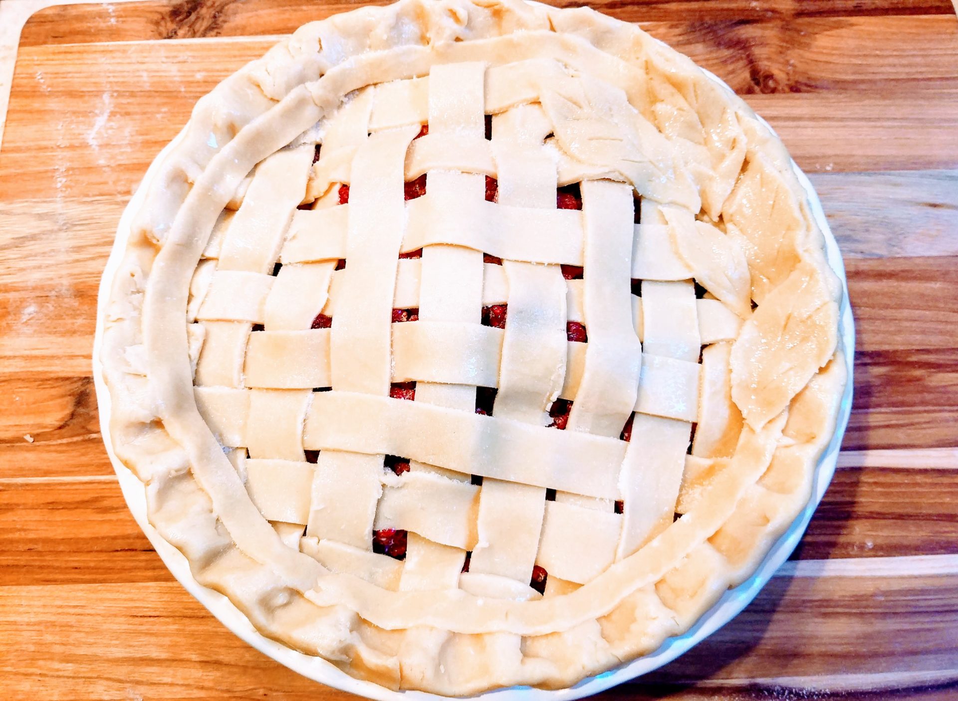A baked gluten free pie with a golden lattice crust on a wooden table, crumbs and a pie server nearby, warm natural kitchen lighting