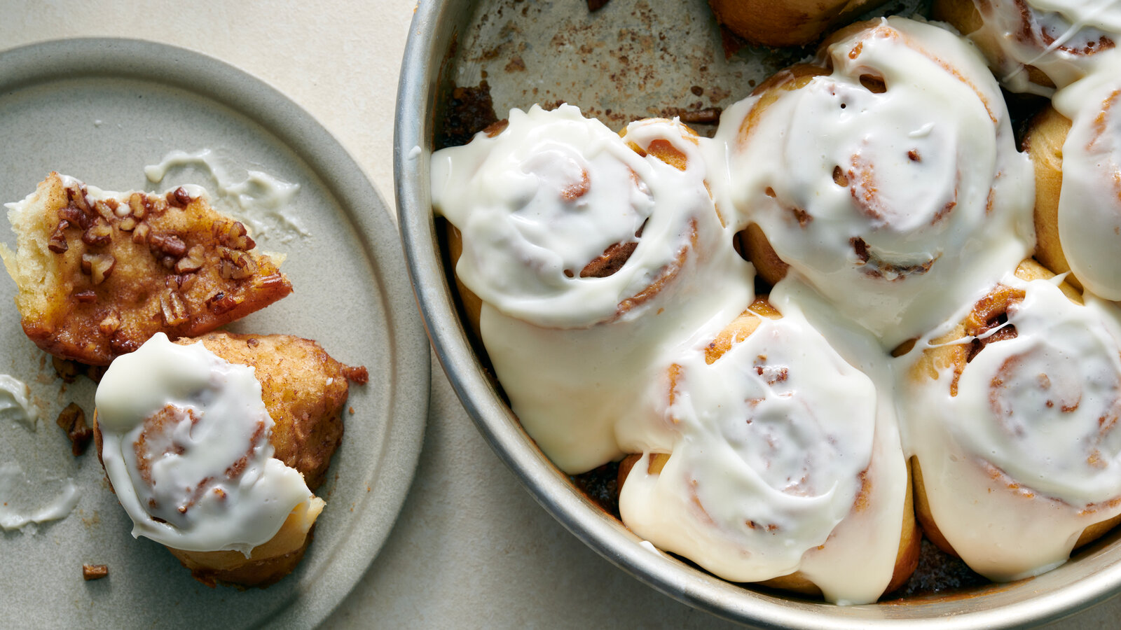A baking dish filled with freshly baked no-yeast cinnamon rolls with a glossy cream cheese glaze dripping into the swirls on a bright kitchen counter