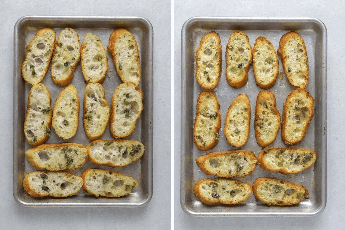 A baking sheet lined with parchment holding golden garlic toast slices with crisp edges and chopped parsley, on a warm kitchen counter