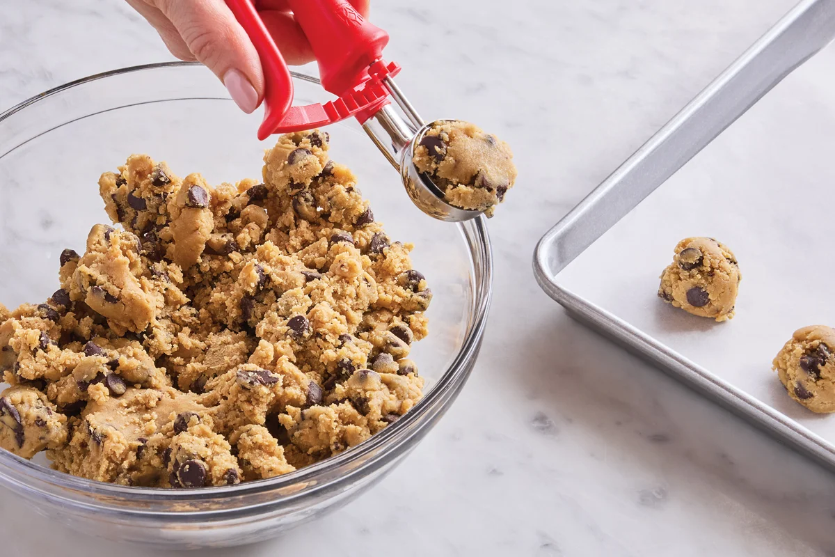 A baking sheet lined with parchment paper holding small scoops of veggie cookie dough ready to go into the oven