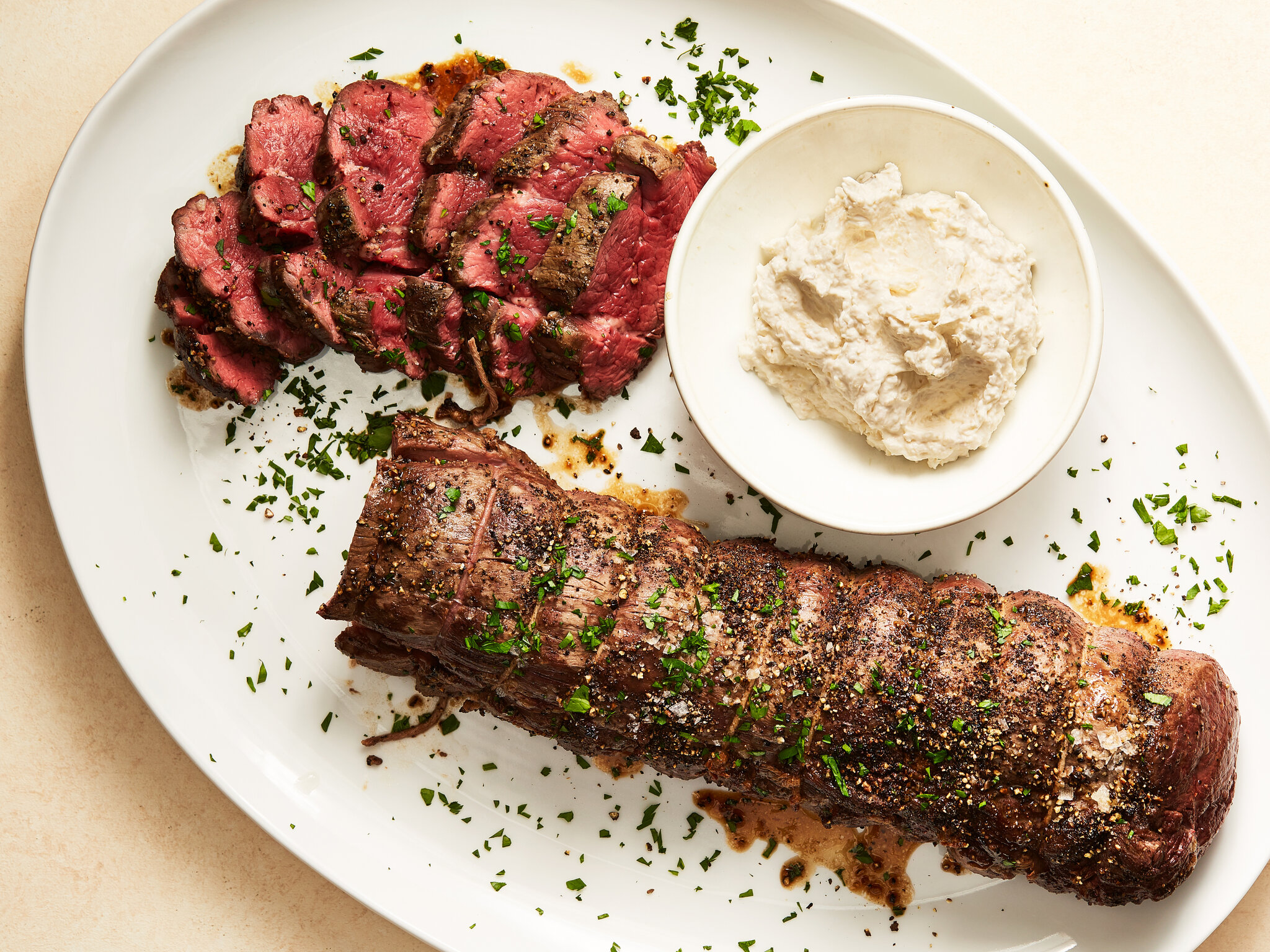 A beef tenderloin roast being seared in a cast iron skillet, with a browned crust forming on the surface.