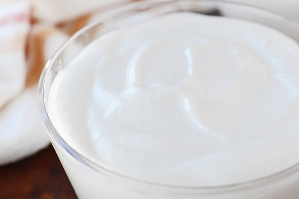 A blender jar filled with smooth, pale creamy sauce made from blended cottage cheese on a kitchen counter