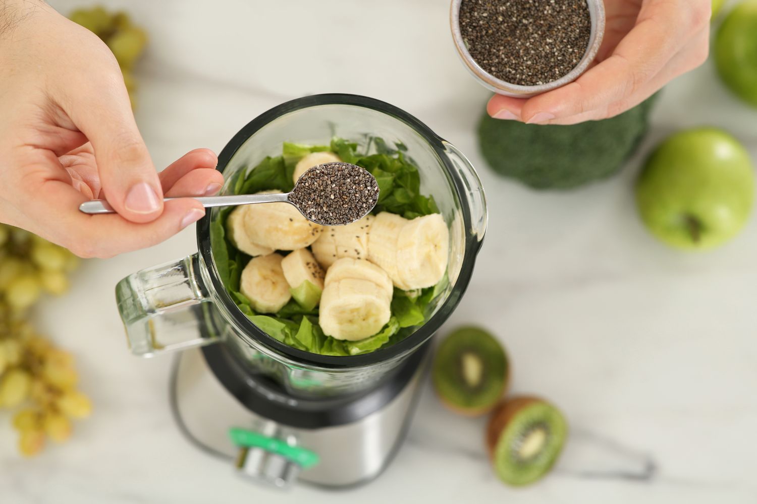 A blender running with a pale vanilla smoothie swirling inside on a light stone kitchen counter