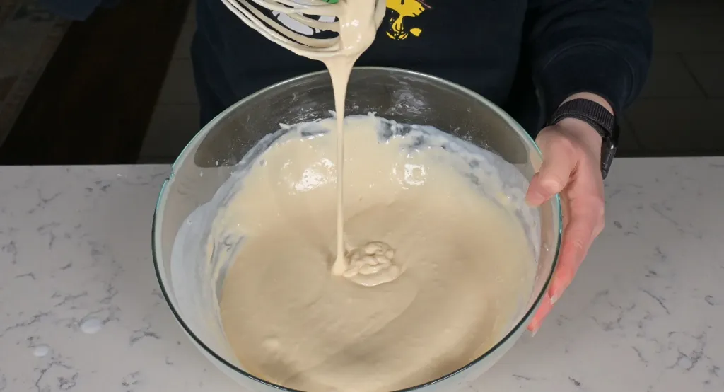 A bowl of aebleskiver batter being whisked until just combined on a light kitchen counter