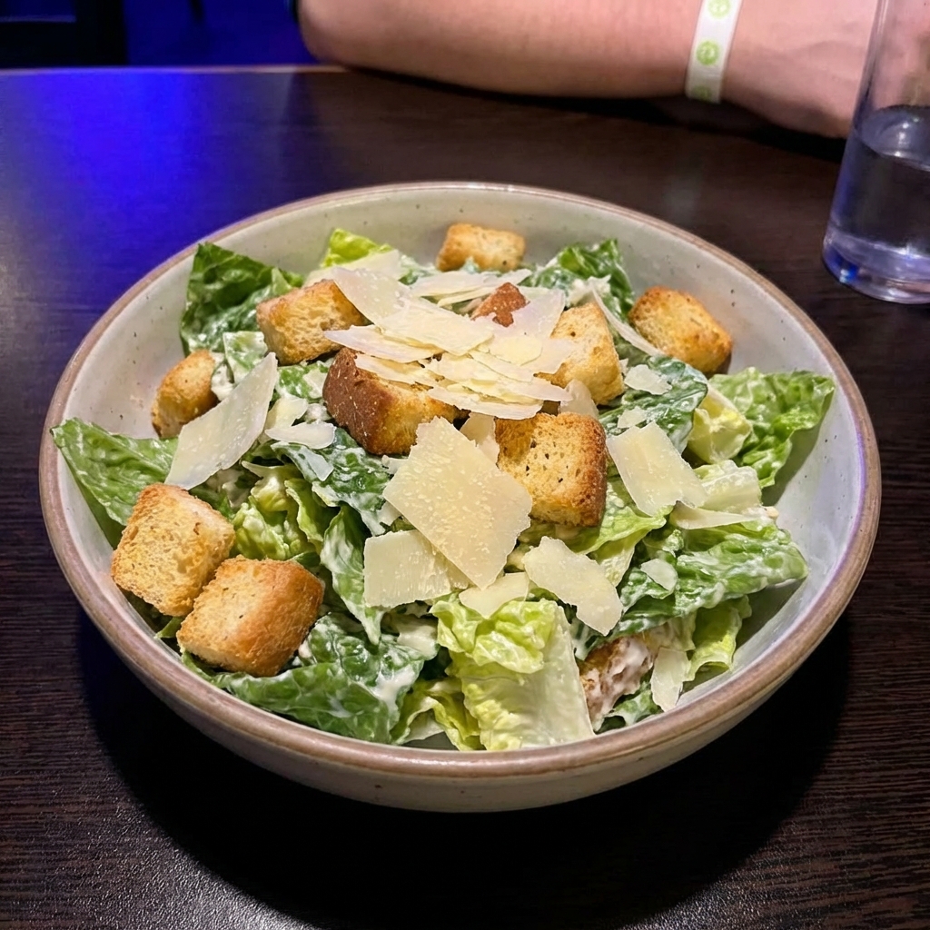 A bowl of classic Caesar salad with croutons and shaved parmesan