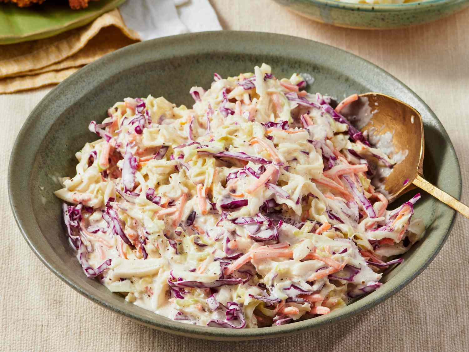 A bowl of creamy coleslaw with shredded cabbage and carrots on a picnic table, bright natural light, photorealistic