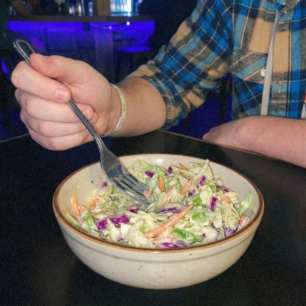 A bowl of crunchy coleslaw with a fork