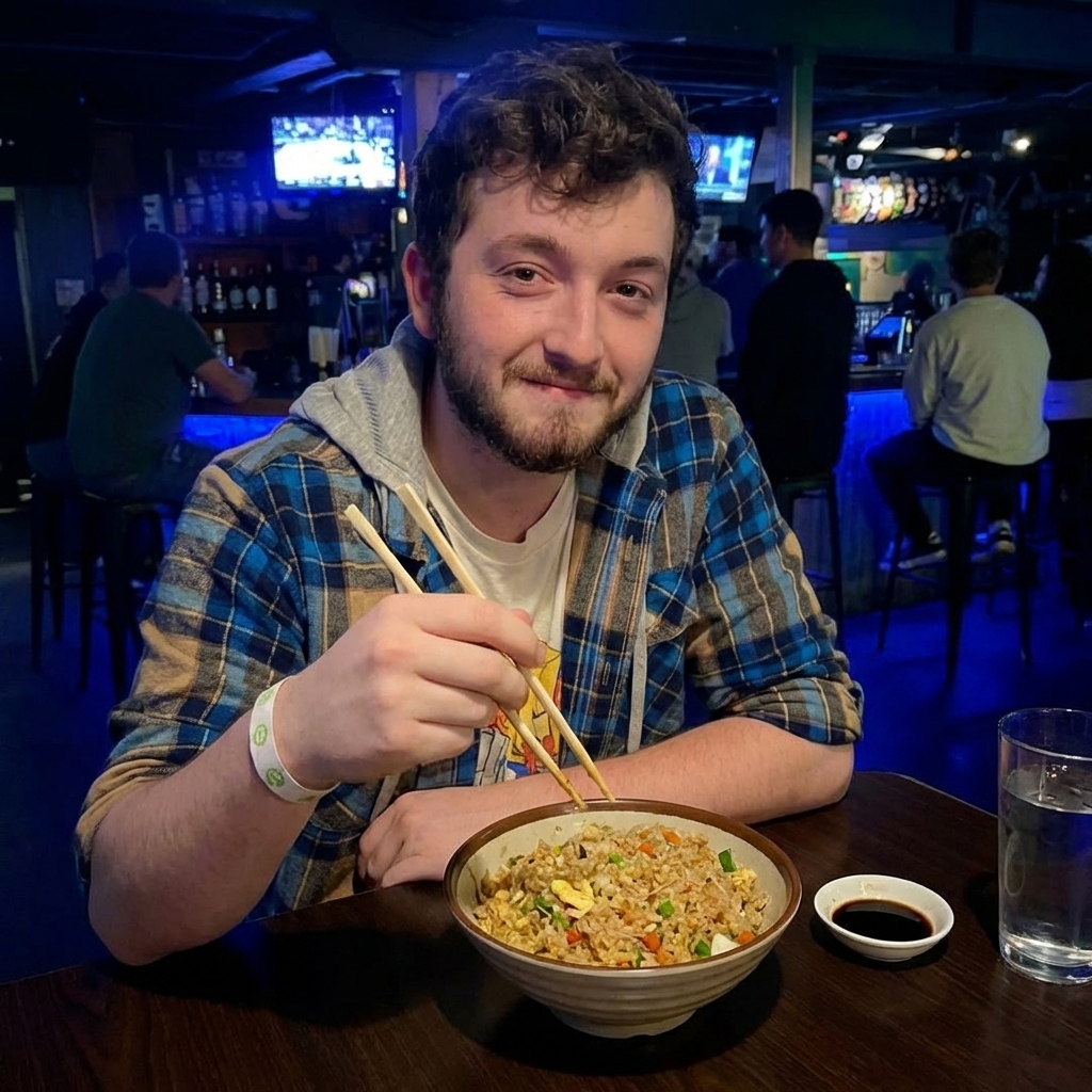 A bowl of fried rice on a wooden table with chopsticks and a small dish of soy sauce nearby