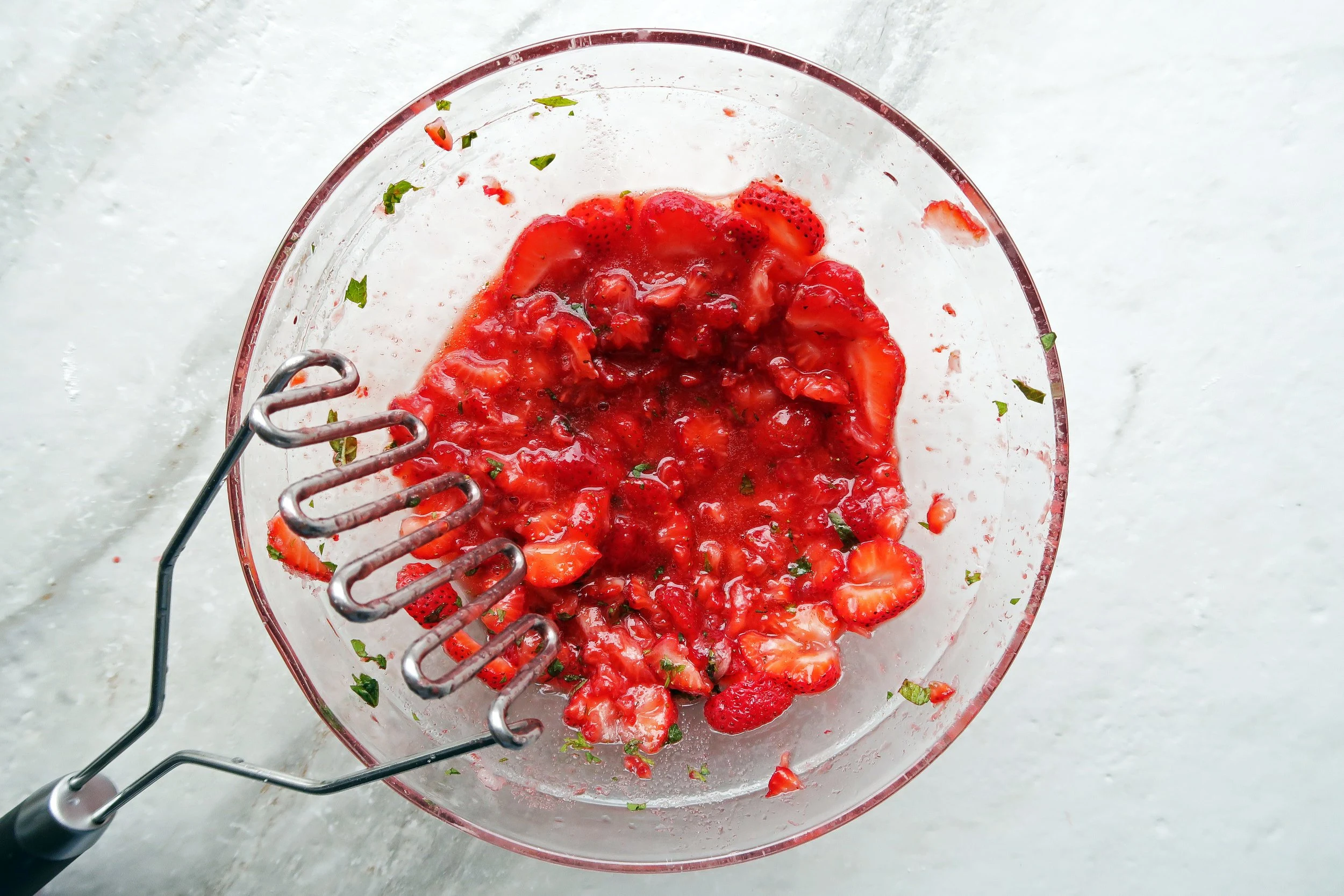 A bowl of mashed strawberries showing a chunky, juicy texture suitable for freezer jam