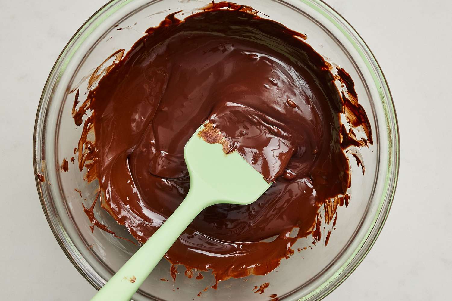 A bowl of melted German sweet chocolate being whisked until smooth on a kitchen counter