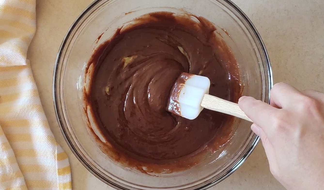 A bowl of melted chocolate and butter being stirred smooth