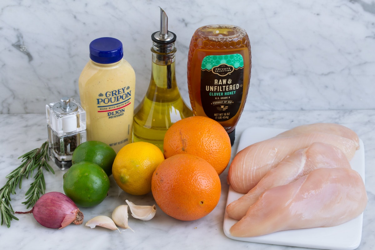 A bowl of orange and lime juice with minced garlic, cumin, smoked paprika, and oregano being whisked together on a kitchen counter