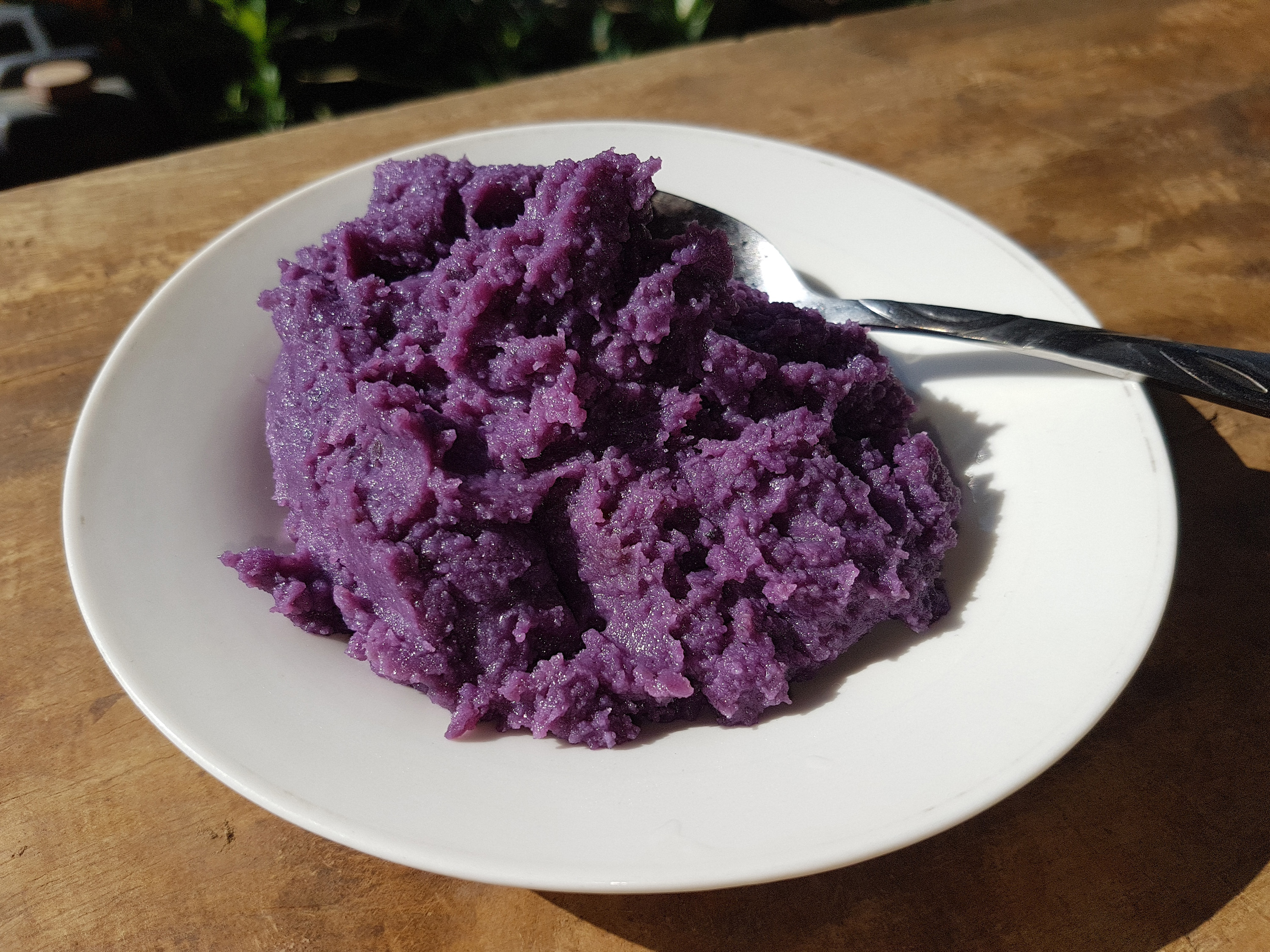 A bowl of vivid purple grated ube on a kitchen counter, ready to be cooked
