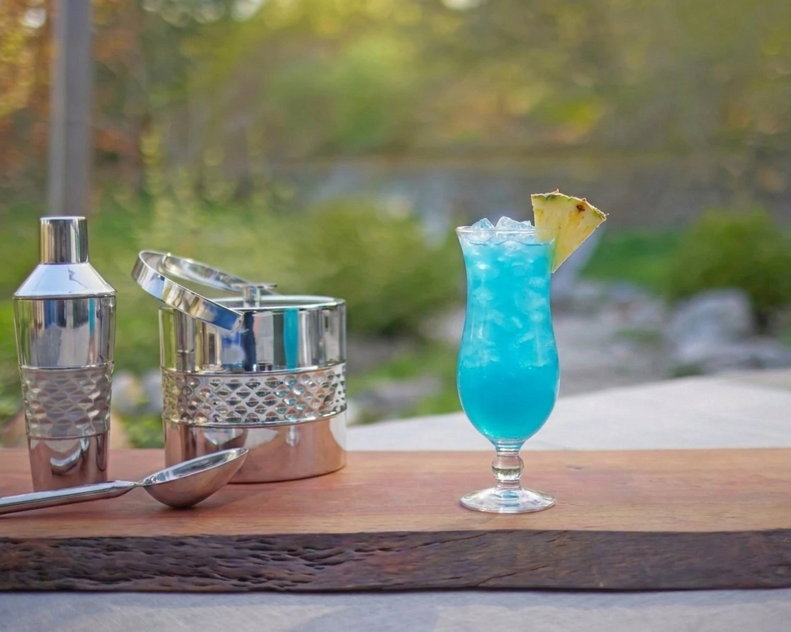 A bright blue cocktail poured over crushed ice in a hurricane glass with a pineapple wedge garnish on a wooden table