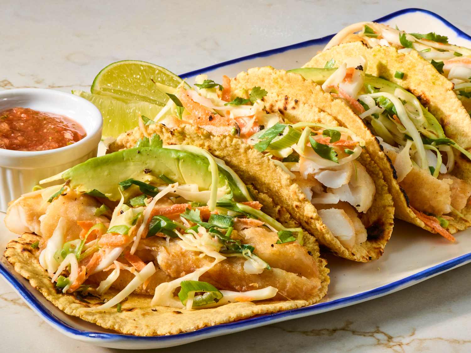 A bright bowl of fish taco slaw made with shredded cabbage, carrots, cilantro, and a creamy lime dressing on a light kitchen counter
