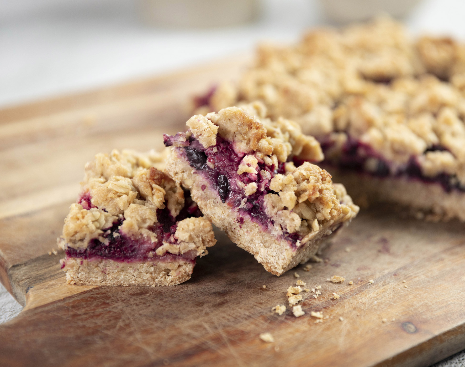 A bubbling mixed berry crumble in a ceramic baking dish with a golden oat topping on a warm kitchen counter