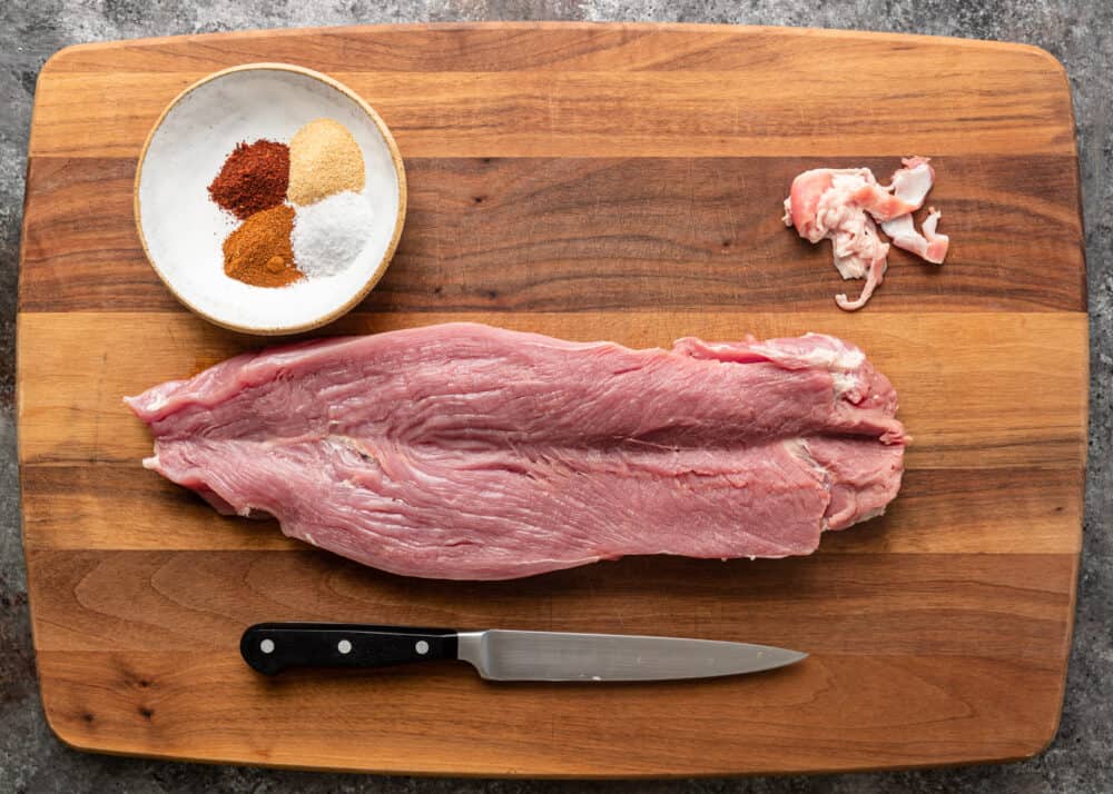 A butterflied pork tenderloin opened flat on a cutting board, ready to be stuffed