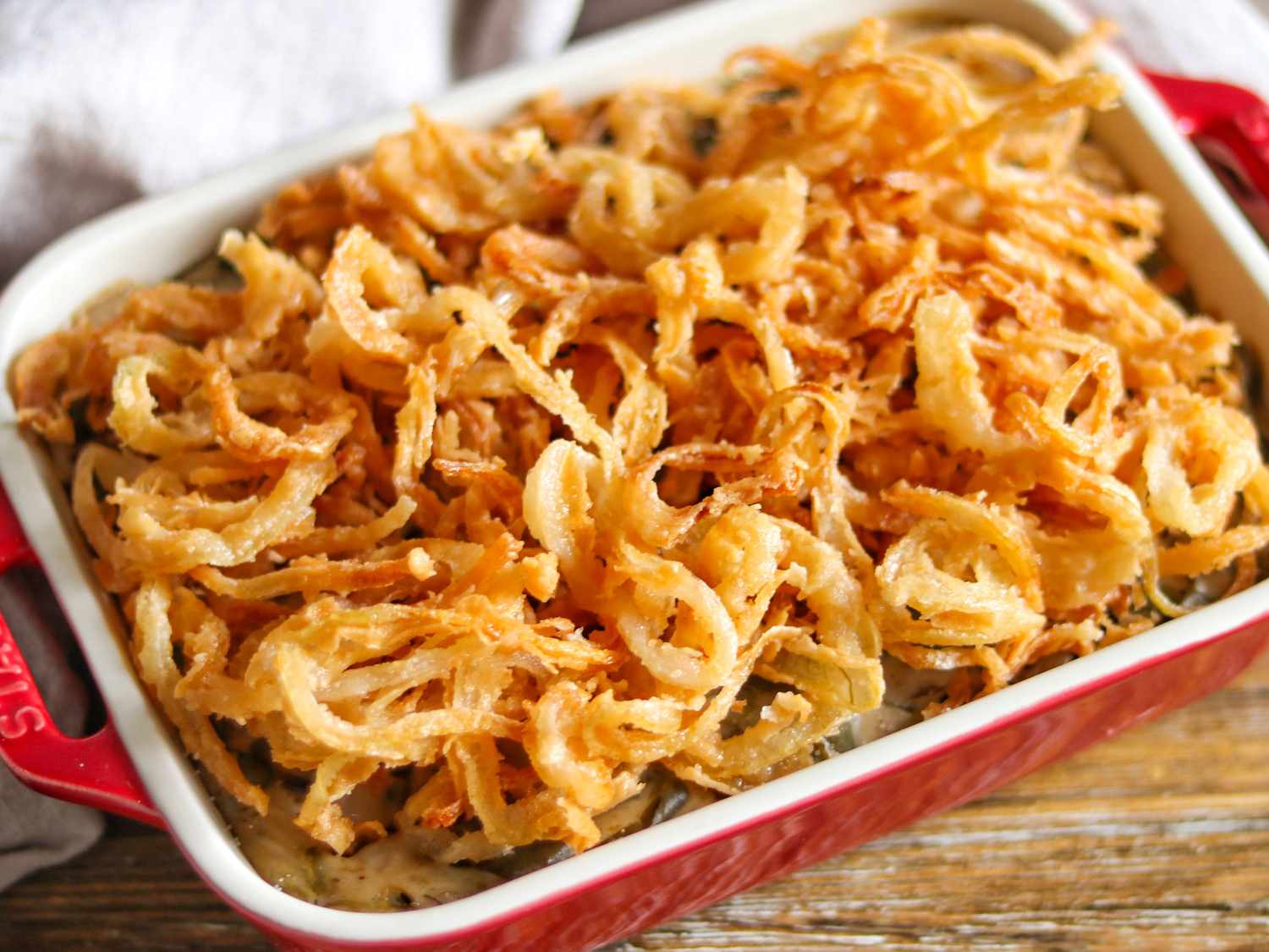 A can of French's Original Crispy Fried Onions next to measured fried onions in a small bowl on a kitchen counter