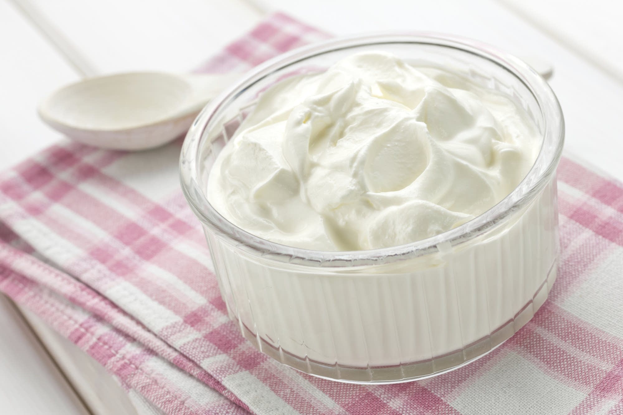 A carton of heavy cream and a small bowl of buttermilk measured out on a clean kitchen counter, ready to mix