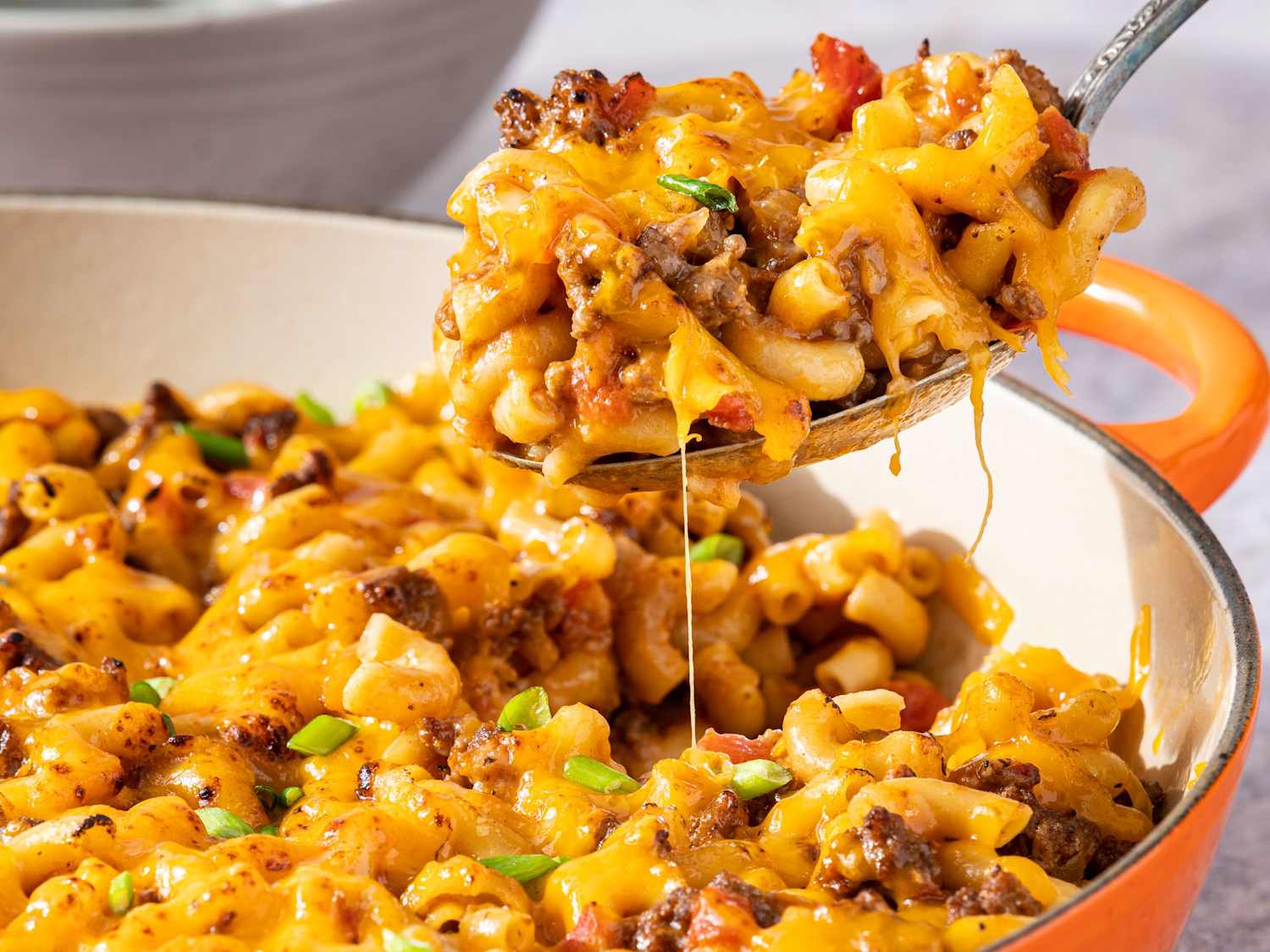 A casserole dish on an oven rack with melted cheese bubbling on top, warm kitchen lighting, oven door open
