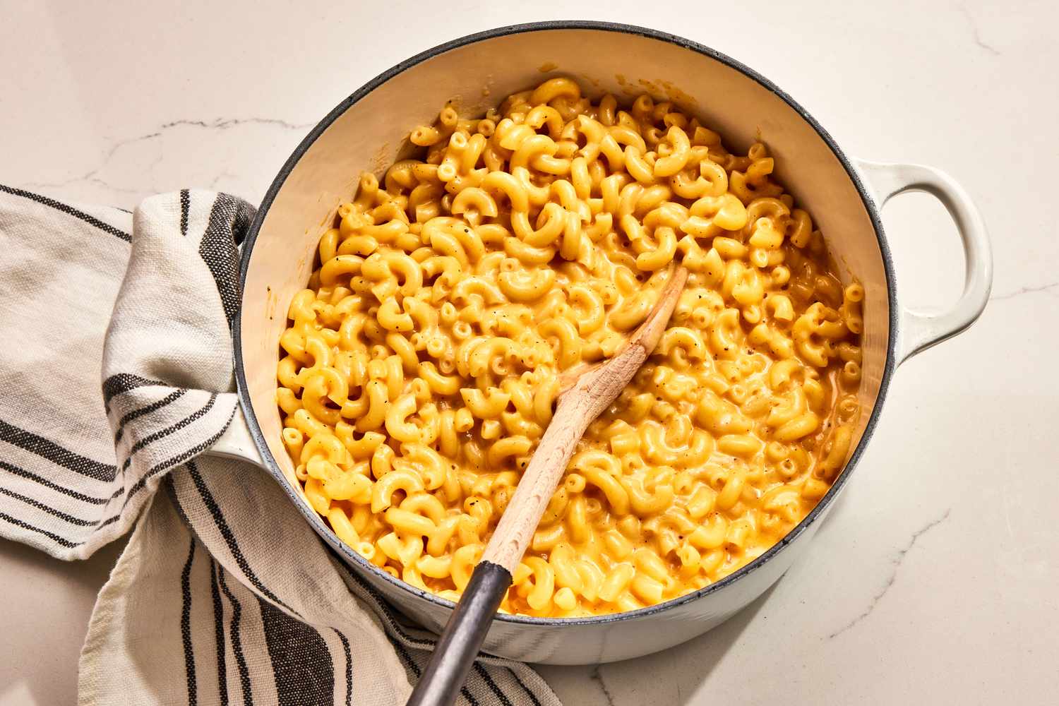 A cast iron skillet filled with creamy stovetop mac and cheese, topped with toasted buttery breadcrumbs, sitting on a warm-toned kitchen counter under soft natural light