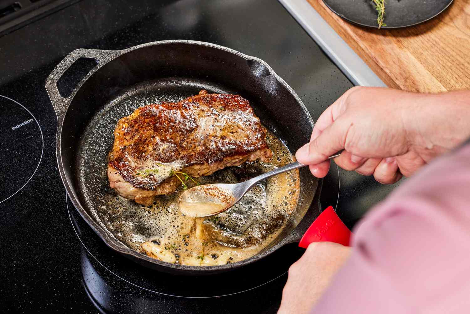 A cast iron skillet heating on a stovetop with a small bowl of butter and lemon nearby on the counter