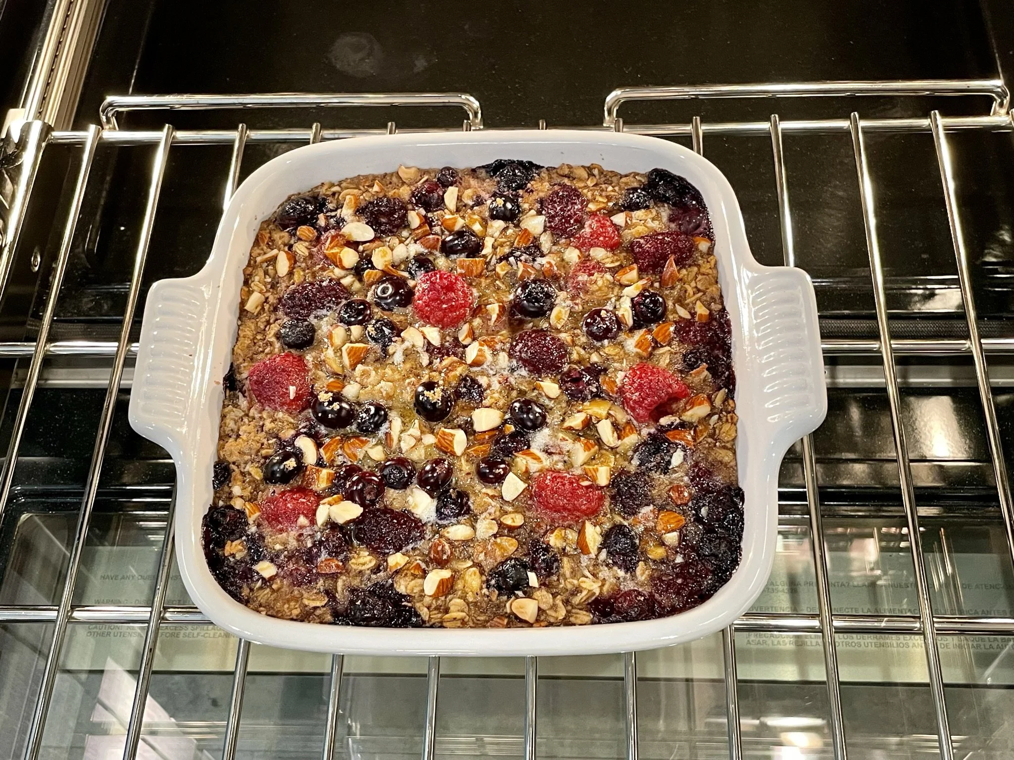 A ceramic baking dish of banana baked oatmeal on an oven rack with the top turning golden brown