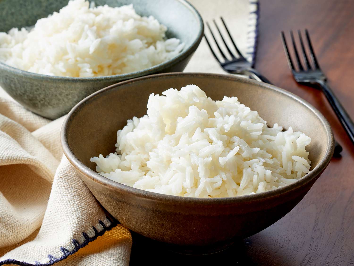 A ceramic bowl filled with fluffy steamed jasmine rice on a dining table, soft natural light, photorealistic food photography