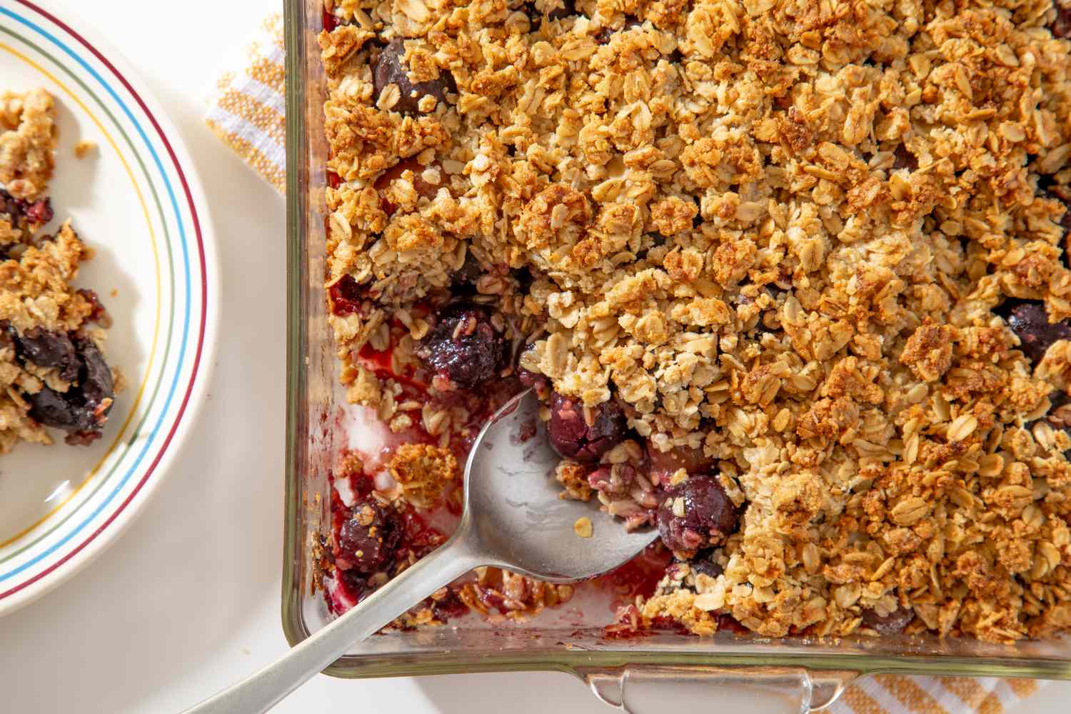 A cherry crisp baking in the oven with golden oat topping and cherry filling bubbling around the edges