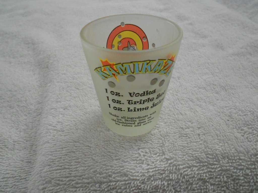 A chilled Kamikaze shot poured into small clear shot glasses on a wooden kitchen counter with a lime wedge nearby, warm natural light