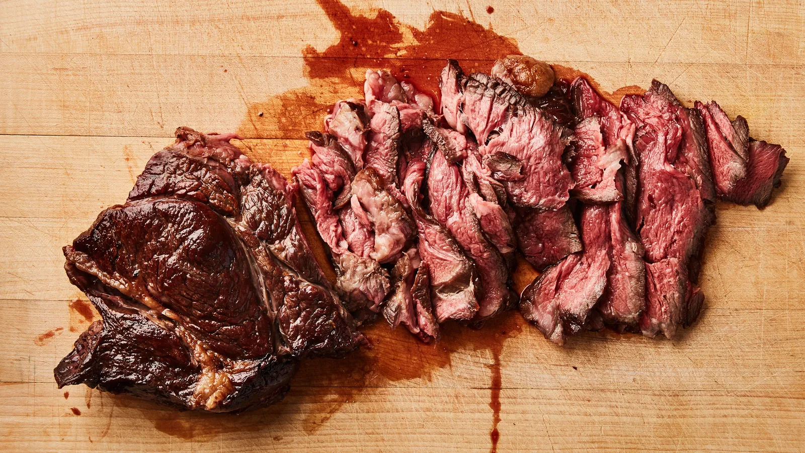 A chuck roast browning in a hot cast iron skillet with deep golden crust forming, seen from above in warm kitchen light