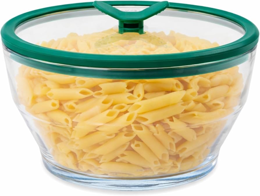 A clear glass meal prep container filled with leftover thyme butter pasta, lid resting nearby on a clean kitchen counter