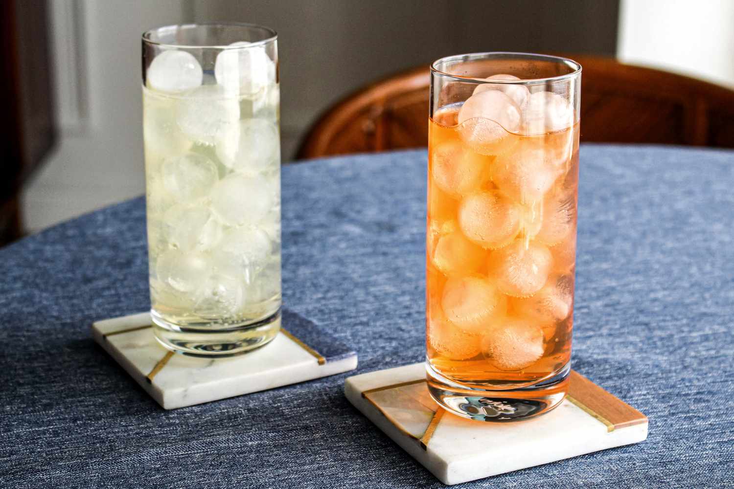 A clear highball glass filled to the top with fresh ice cubes on a bright kitchen counter