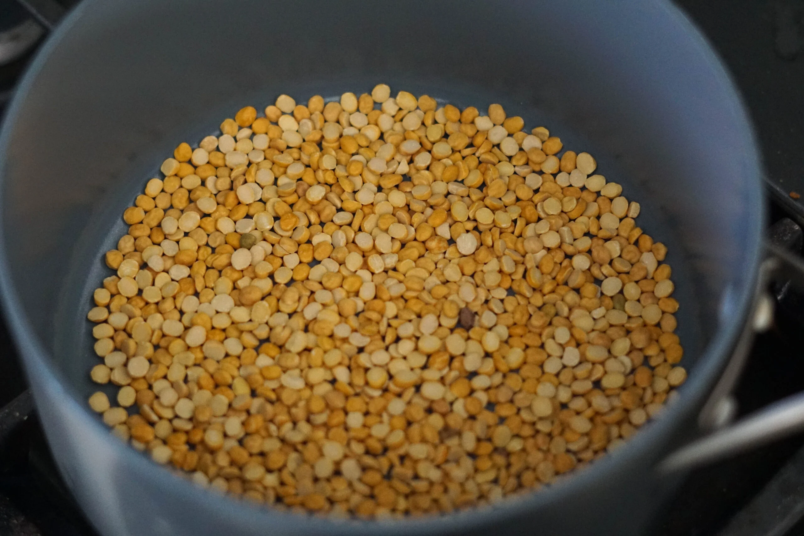 A close-up of grated coconut in a bowl next to roasted chana dal on a small plate on a kitchen counter