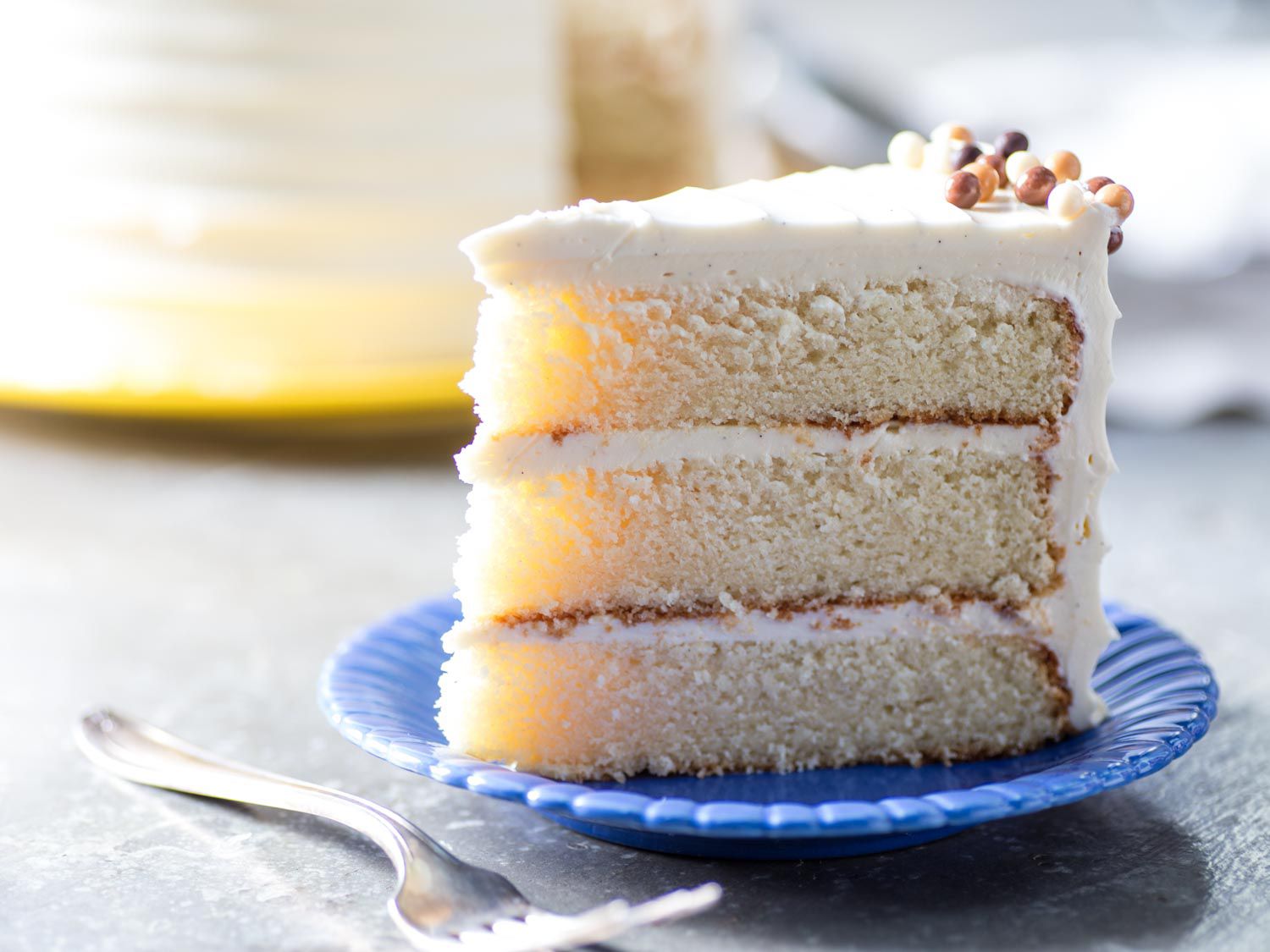 A close-up photo of a moist cake slice showing a tender crumb with a smooth layer of frosting on top