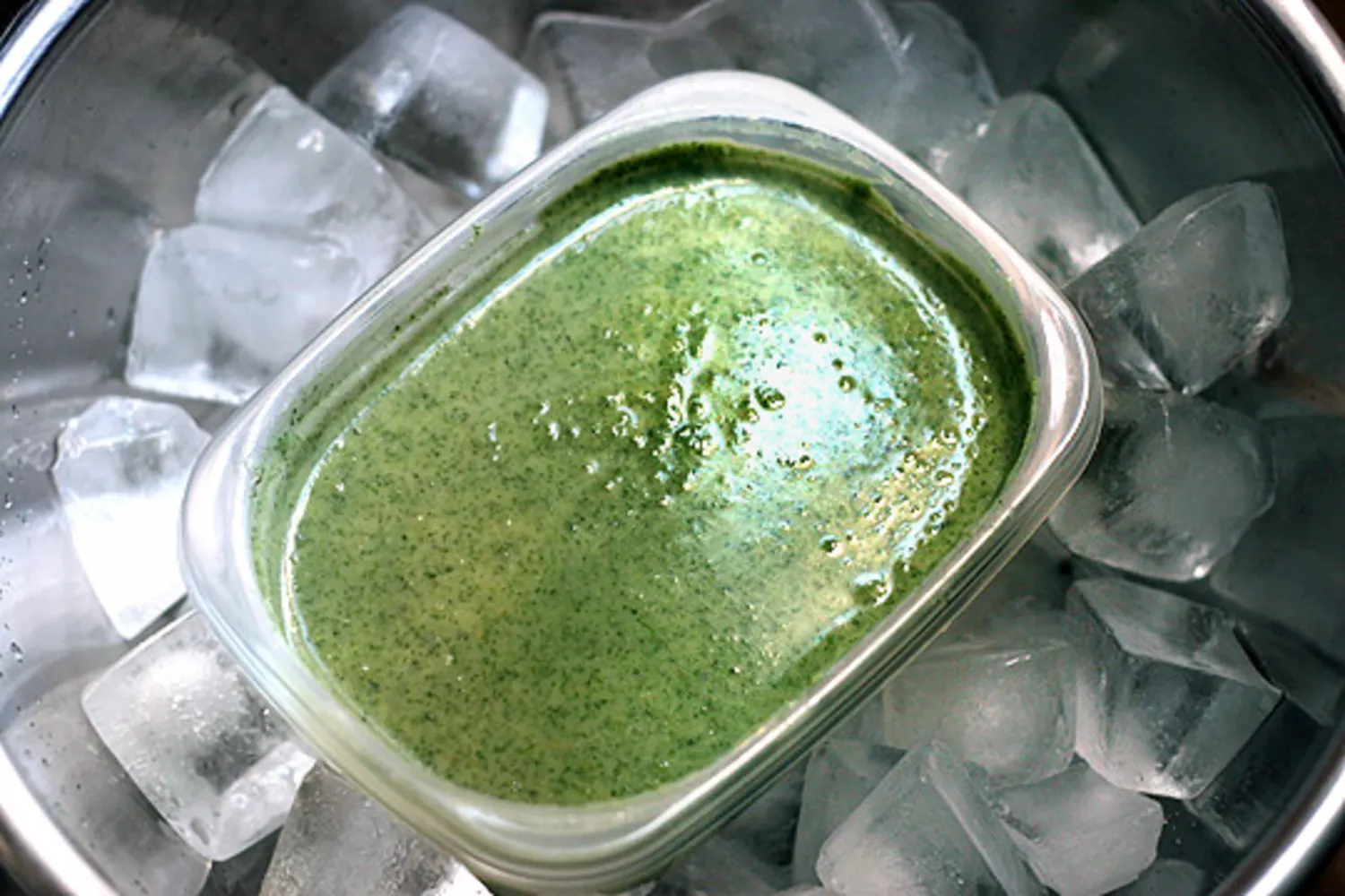 A container of strained broth set in an ice water bath to cool