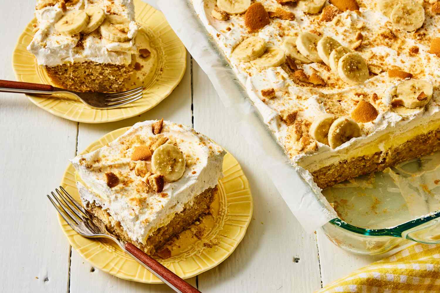 A covered baking pan of banana pudding cake resting on a refrigerator shelf, with a serving spatula nearby