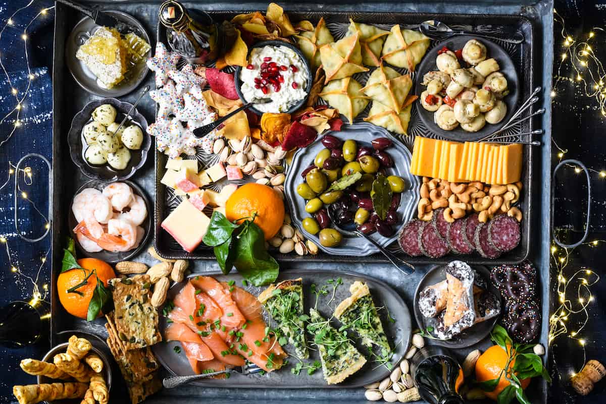 A cozy New Year’s party snack table with a platter of crispy potato bites, small bowls of dip, and simple candlelight on a neutral kitchen counter