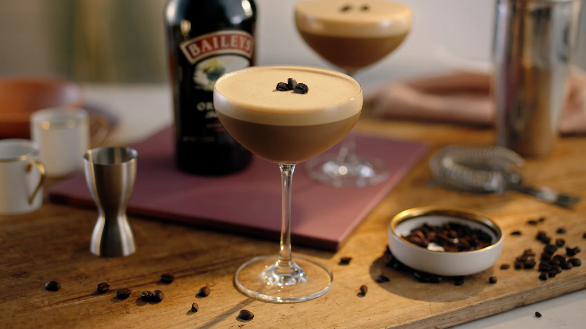 A creamy espresso martini made with Baileys in a chilled coupe glass, topped with thick coffee foam and three coffee beans
