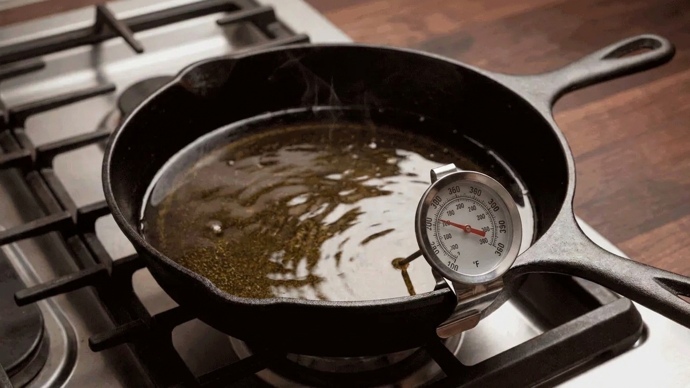 A deep skillet on a stove with hot oil and a clip-on thermometer reading around 360 degrees Fahrenheit