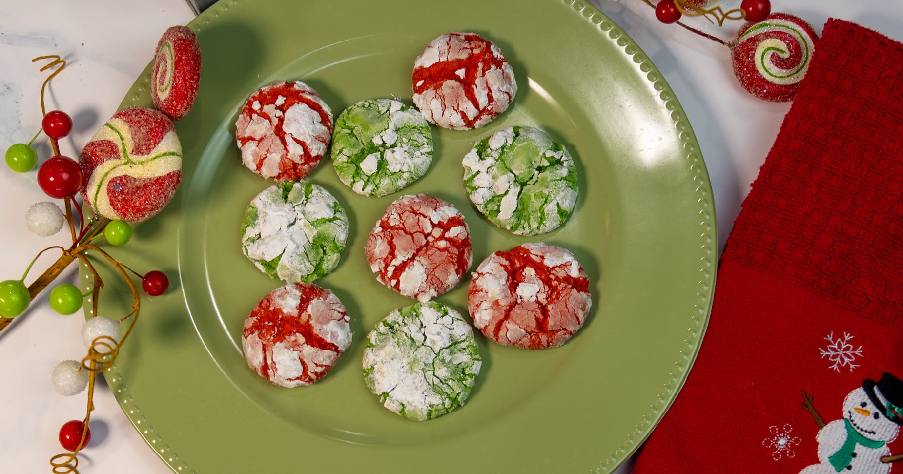 A festive platter of chocolate Christmas crinkle cookies with powdered sugar crackles on a wooden table with soft holiday lights in the background
