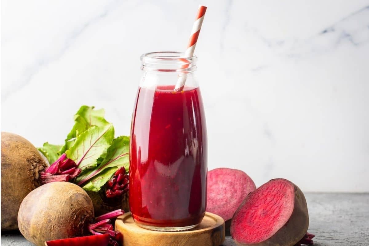 A fine-mesh sieve set over a glass bowl while beet juice is strained on a kitchen counter