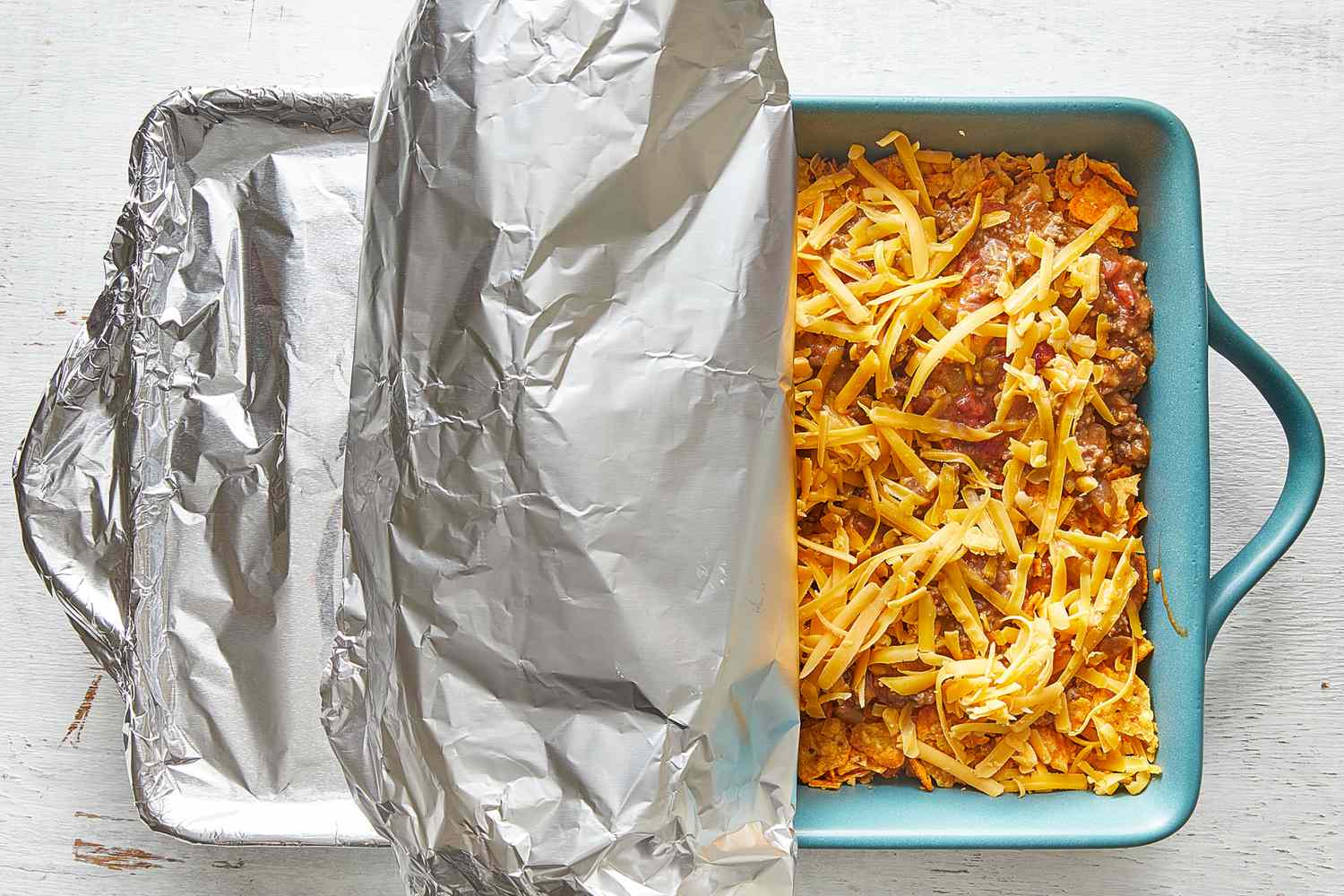A foil-covered casserole dish on a kitchen counter, ready to bake cabbage rolls in tomato sauce