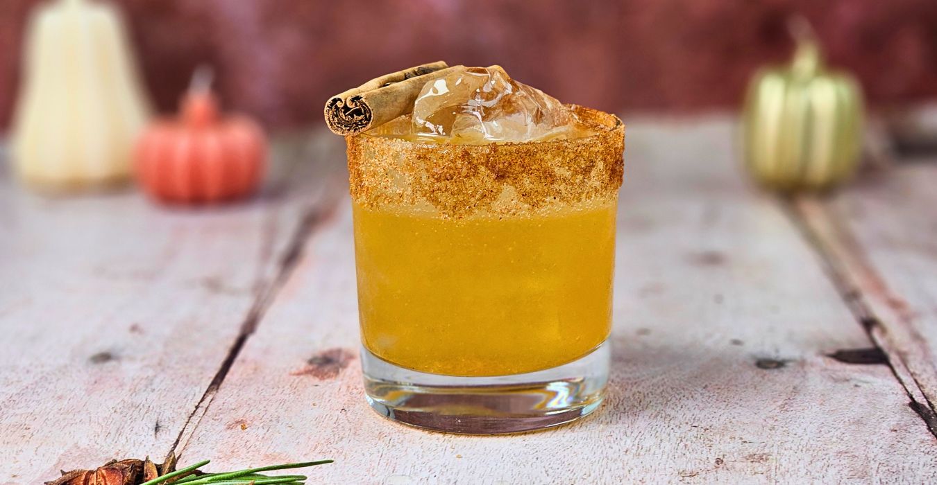 A glass being dipped into honey and then into cinnamon sugar on a kitchen counter