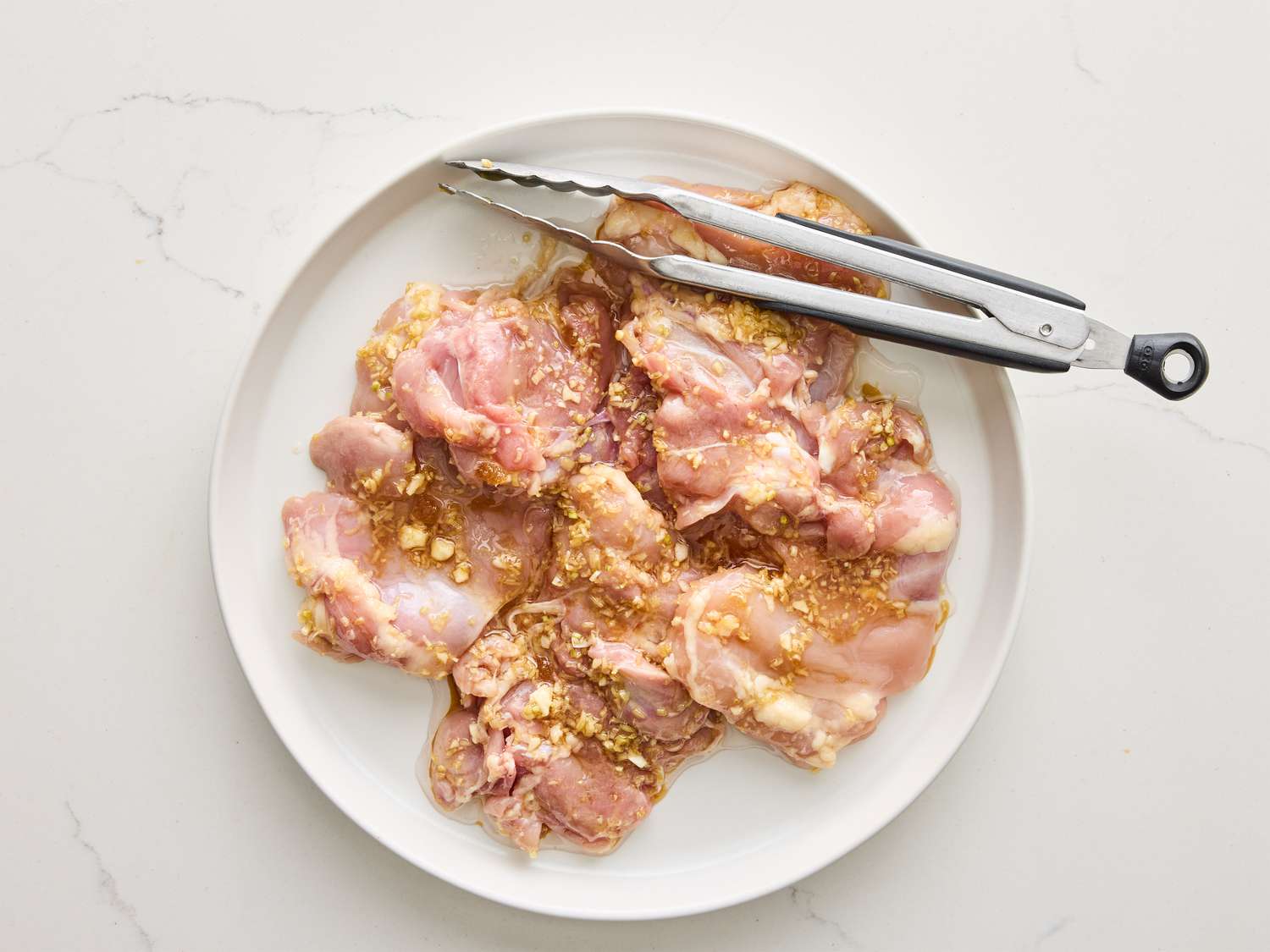 A glass bowl with lemongrass chicken marinade being whisked with a fork on a kitchen counter