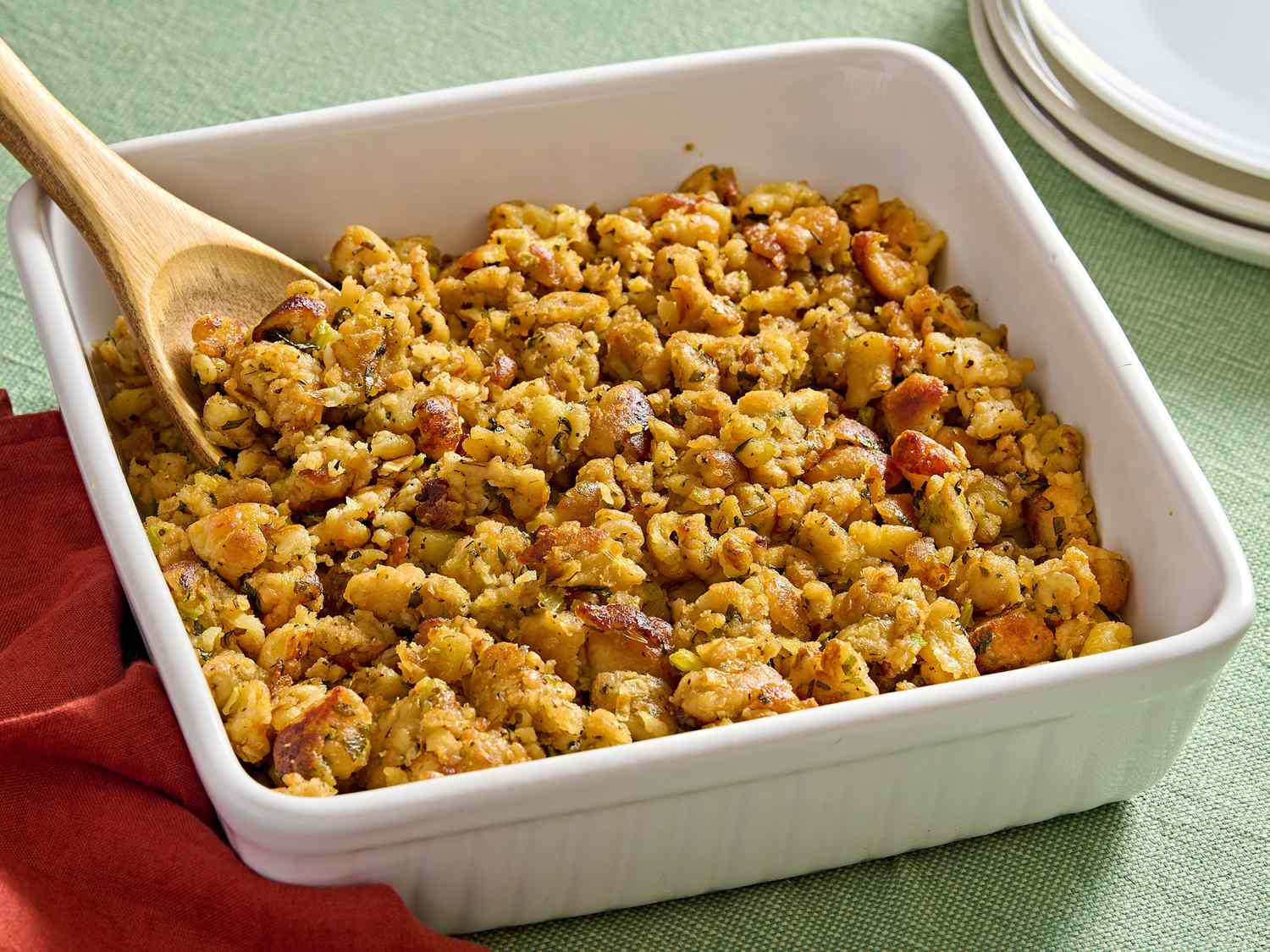 A glass food storage container filled with leftover stuffing with the lid set beside it on a kitchen counter