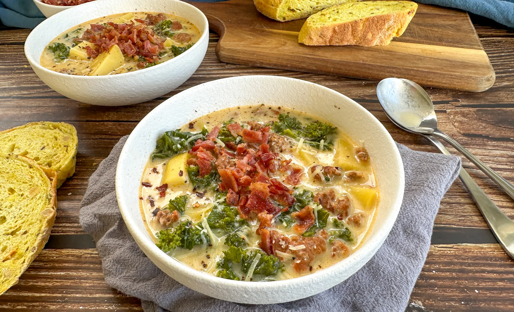 A glass meal prep container filled with leftover Sopa Toscana soup, lid off, sitting on a kitchen counter next to a ladle